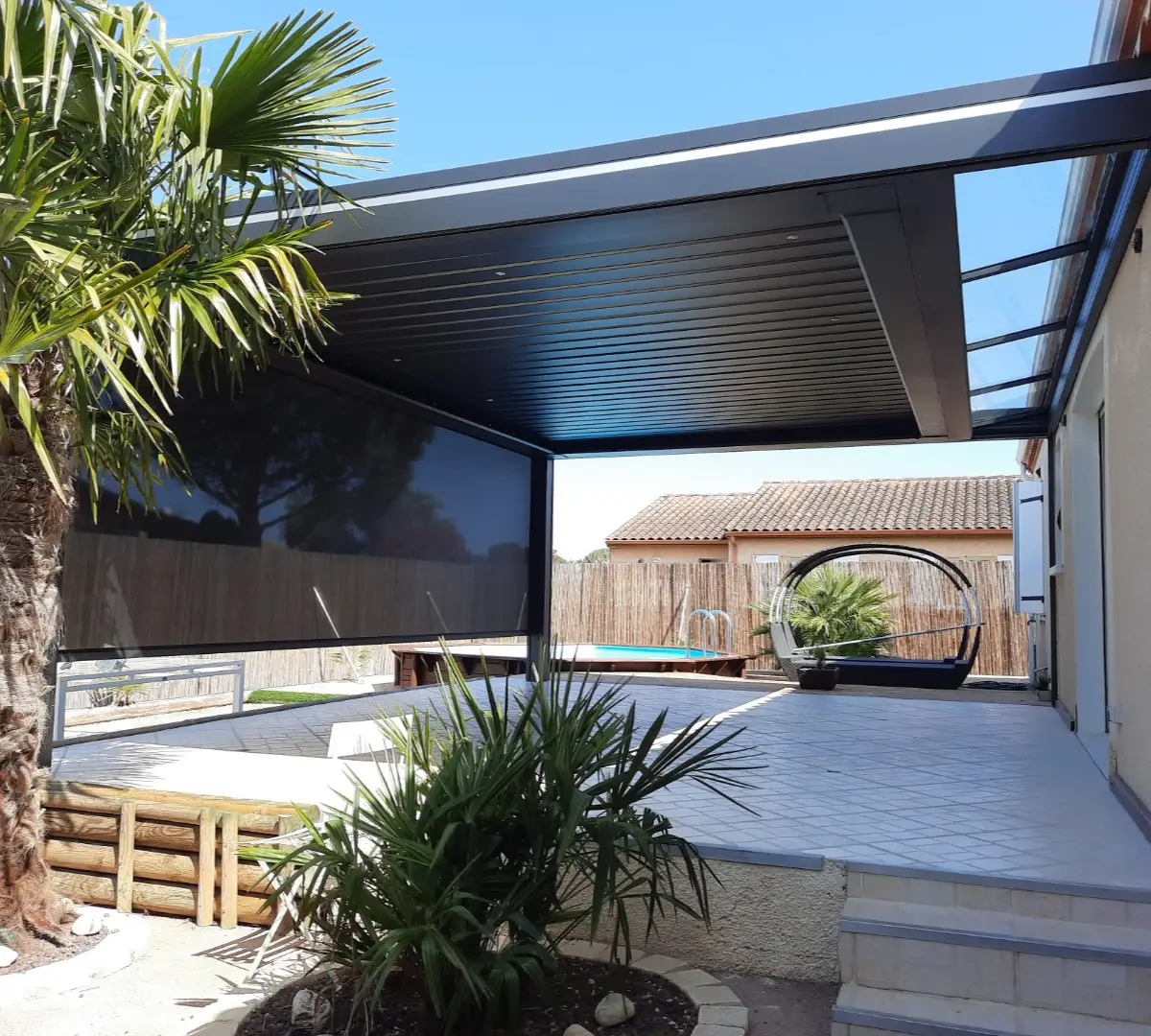 Pergola noir avec une avancée en verre pour apporter de la lumière naturelle à la maison.